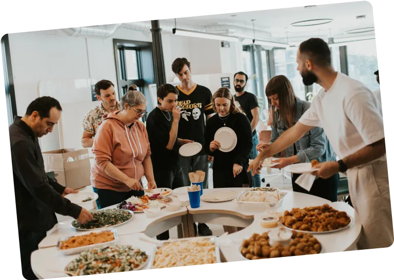 Photo of employees gather around a table of food