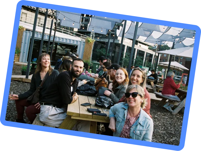 Photo of employees sitting outside on a picnic table