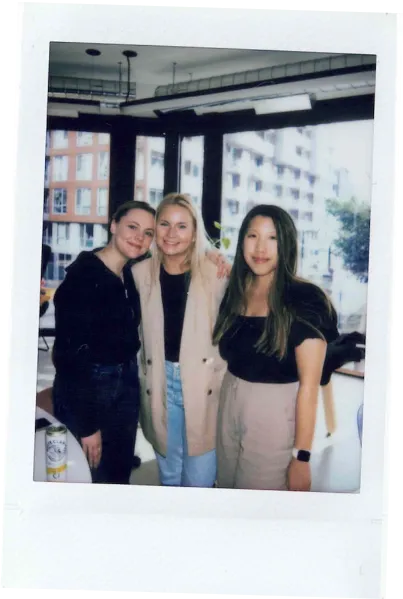 Polaroid of 3 employees smiling at the camera indoor